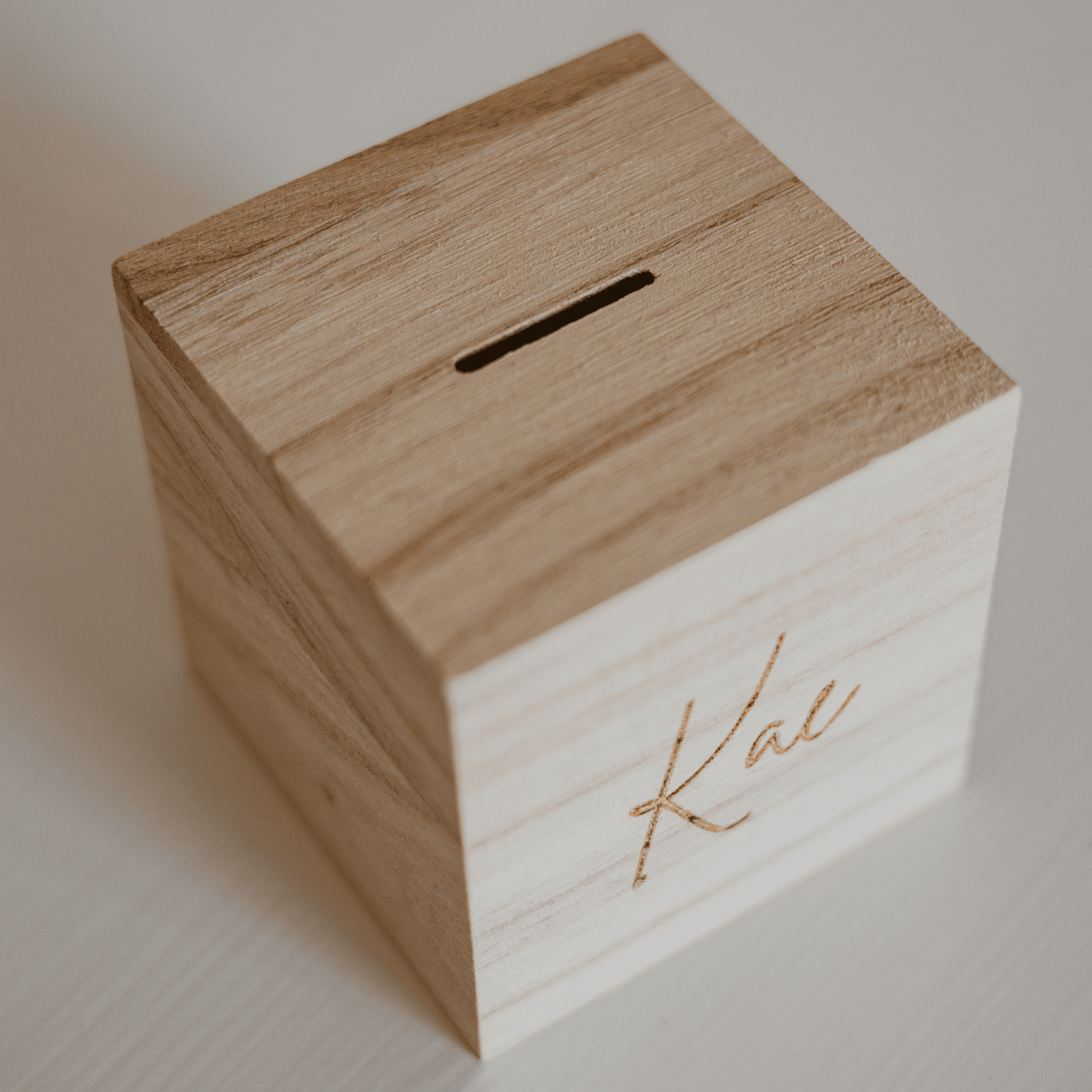 Houten spaarpot met naam - bovenzijde – een gepersonaliseerde spaarpot met gravure, ideaal als uniek cadeau. Deze houten spaarpot met naam is perfect voor kinderen om op een speelse manier te sparen.